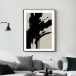 Bold black brushstrokes on white canvas above gray sofa in minimalist living room.