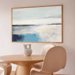 Abstract seascape canvas with blue horizon in minimalist interior with wooden table.