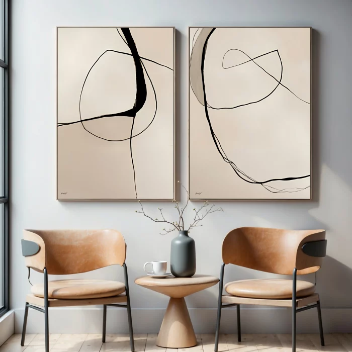 Abstract black line art diptych over minimalist leather chairs with accent table.