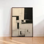 Minimalist geometric abstract artwork in black frame on wooden floor against white wall.