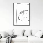 Abstract line drawing artwork in black frame above white modern sofa.
