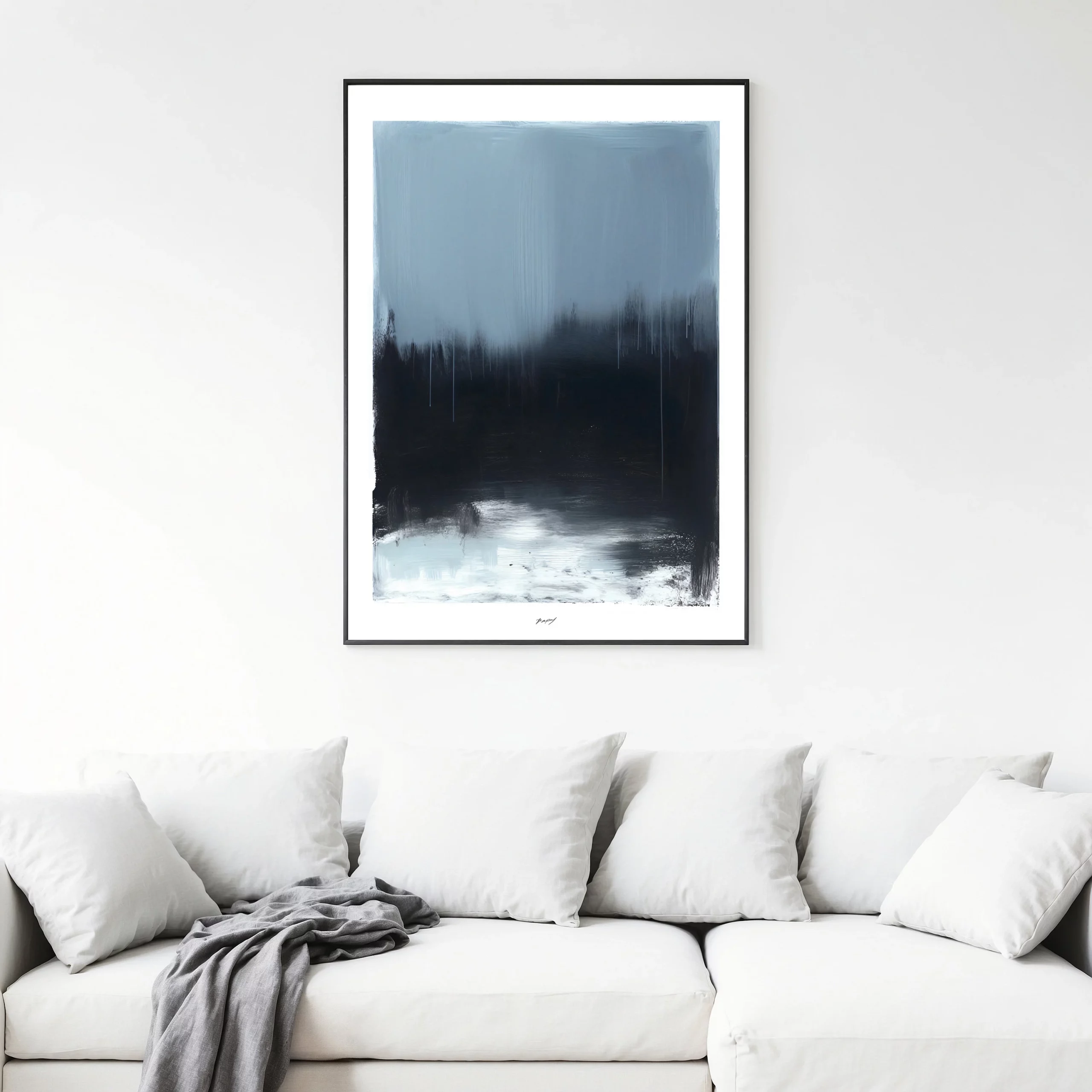 Minimalist winter forest print with dark silhouettes above white contemporary sofa.