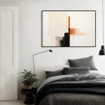 Minimalist bedroom with abstract wall art in beige, rust and black tones.