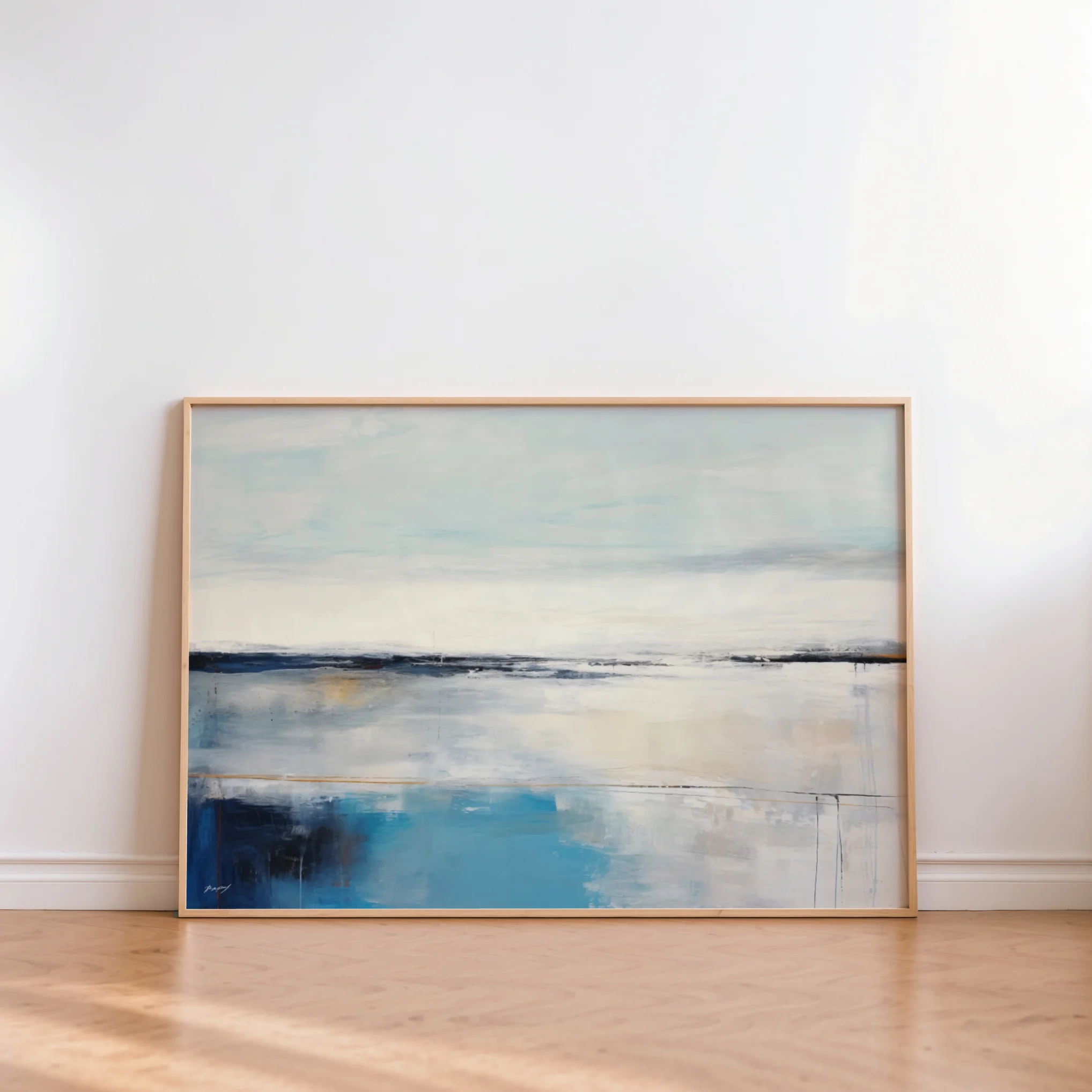 Framed abstract seascape painting with blue water and sky tones leaning against white wall.