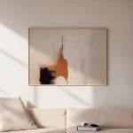 Abstract artwork with terracotta and black tones displayed above a cream sofa in sunlit room.