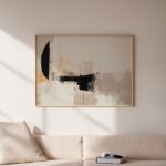 Abstract black brushstrokes on neutral canvas above cream sofa in minimalist living room