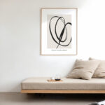 Minimalist black brushstroke abstract art above wooden bench with beige cushion and pillows.