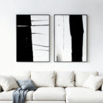 Abstract black and white diptych artwork displayed above white sofa in modern living room.