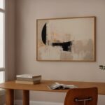 Abstract black and beige minimalist artwork in wooden frame above desk by window.