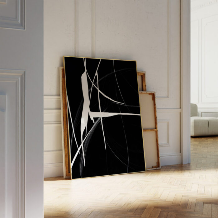 Black and white abstract canvas with dynamic lines leaning against a white wall in minimalist interior.