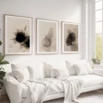 Abstract wabi-sabi triptych art displayed above white sofa in minimalist living room.
