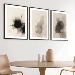 Abstract triptych artwork in black and beige tones above wooden dining table.