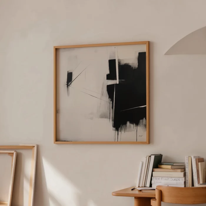 Bold black and white abstract art in wooden frame above minimalist shelf display.