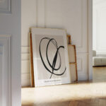 Elegant black brushstroke abstract print leaning against white wall in minimalist interior space.