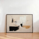 Abstract black and beige wall art with geometric shapes on wooden floor.