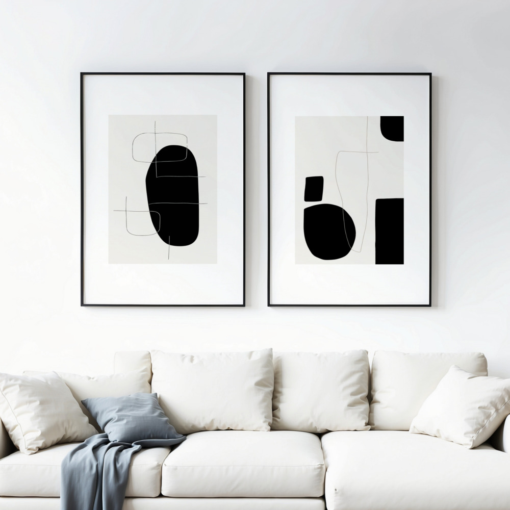 Minimalist black geometric art prints above white sofa in contemporary living space.