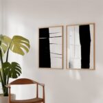 Monstera plant beside two black and white abstract art prints in minimalist interior.