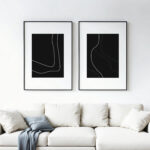 Minimalist black and white abstract line art duo hanging above cream sofa