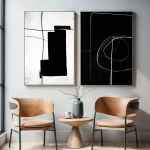 Minimalist abstract black and white geometric prints above contemporary caramel chairs and table.