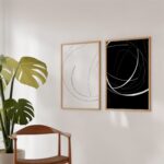 Minimalist black and white art prints with wooden frames beside lush monstera plant.