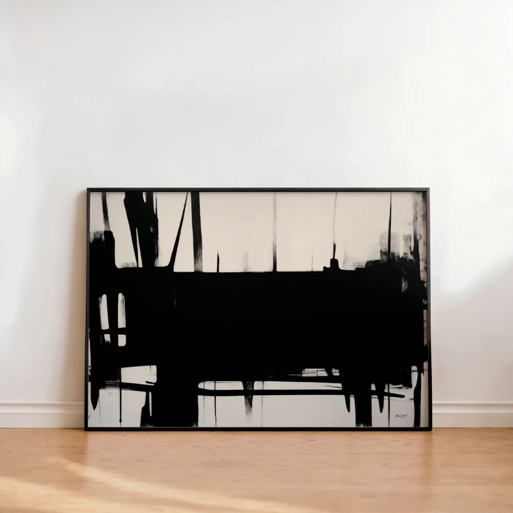 Bold black brushstrokes on white canvas in minimalist frame leaning against wall.