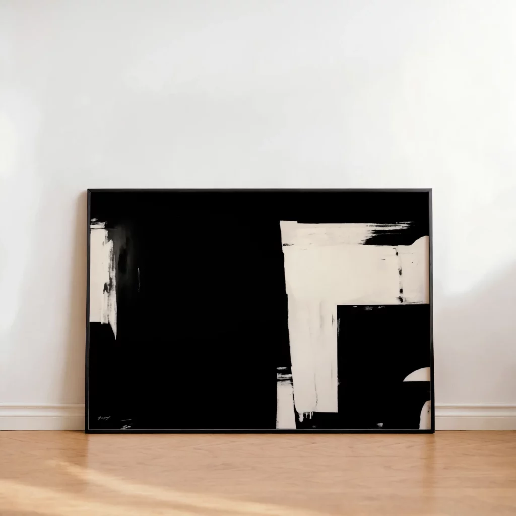 Black and white abstract painting with angular brushstrokes on wooden floor against white wall.