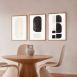 Minimalist dining area with round wooden table and abstract black and white gallery wall.
