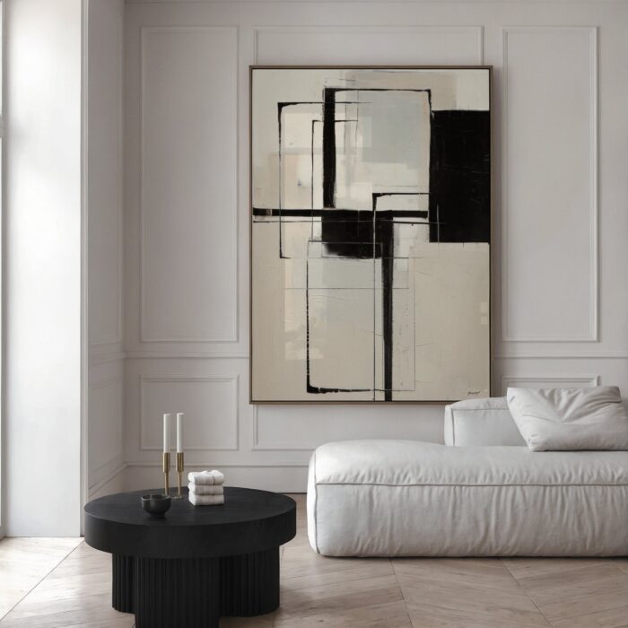 Minimalist geometric abstract painting in black and beige above white sofa with black table.