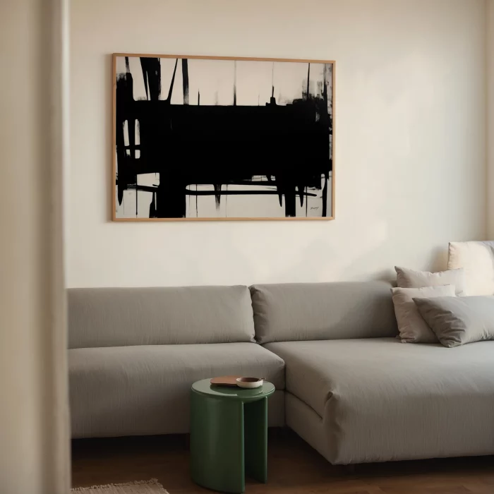 Minimalist living room featuring dramatic black brushstroke art above gray sectional sofa.