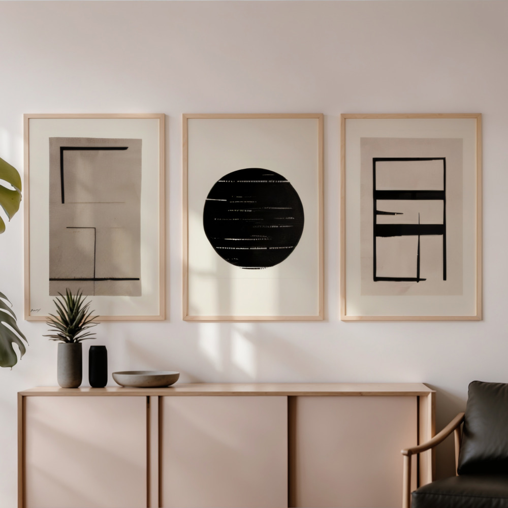 Minimalist wall art trio above light wood sideboard in neutral modern interior