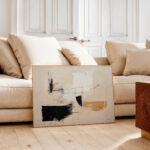 Abstract minimalist painting with beige and black tones against neutral living room interior.