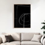 Minimalist black and white abstract line art mounted above a neutral sofa.