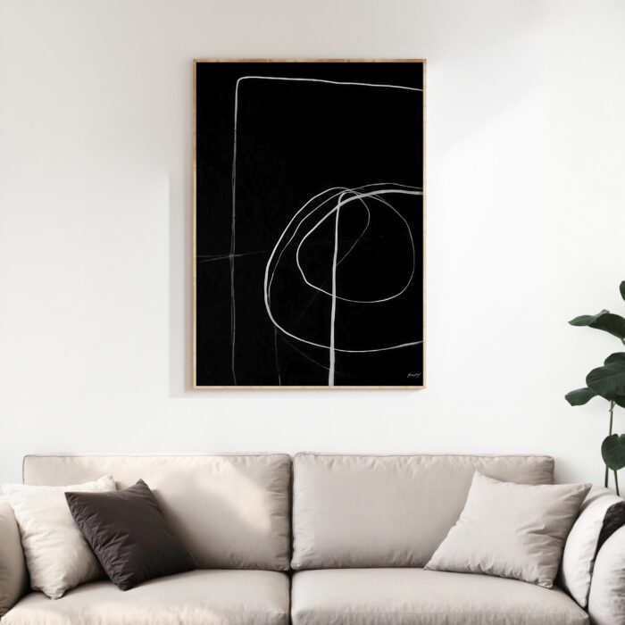 Minimalist black and white abstract line art mounted above a neutral sofa.