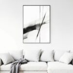 Abstract black brushstrokes artwork above white sofa in minimalist living room.