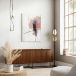 Minimalist abstract artwork in earth tones above modern wooden credenza with pampas grass decor.