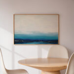 Abstract seascape painting over wooden table with white chair in minimalist dining area.