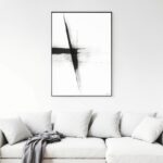 Minimalist black brushstroke artwork on white wall above cream sofa with neutral cushions.