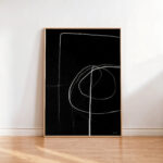 Minimalist black canvas with white flowing lines in wooden frame against white wall.