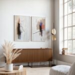 Abstract art duo above mid-century wooden credenza in minimalist interior space.