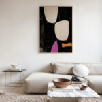 Colorful geometric abstract art hanging above white sofa in minimalist living room.