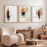 Abstract wall art trio over wooden console in minimalist contemporary living space.