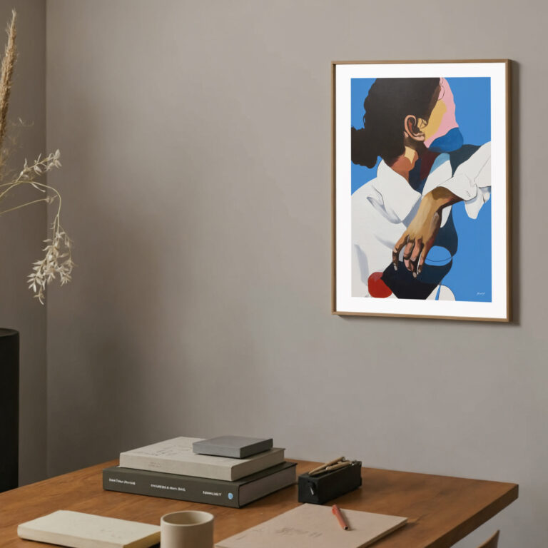 Abstract artwork with blue and pink forms above wooden desk with books and mug.