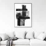 Abstract black brushstrokes artwork displayed above white sofa with gray throw blanket.