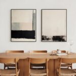 Black and beige abstract canvas art over wooden dining table with mid-century chairs.
