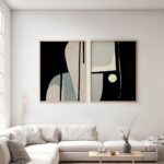Abstract black and beige diptych artwork displayed above white sofa in bright living room.