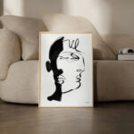 Minimalist black and white face line drawing in wooden frame against neutral interior