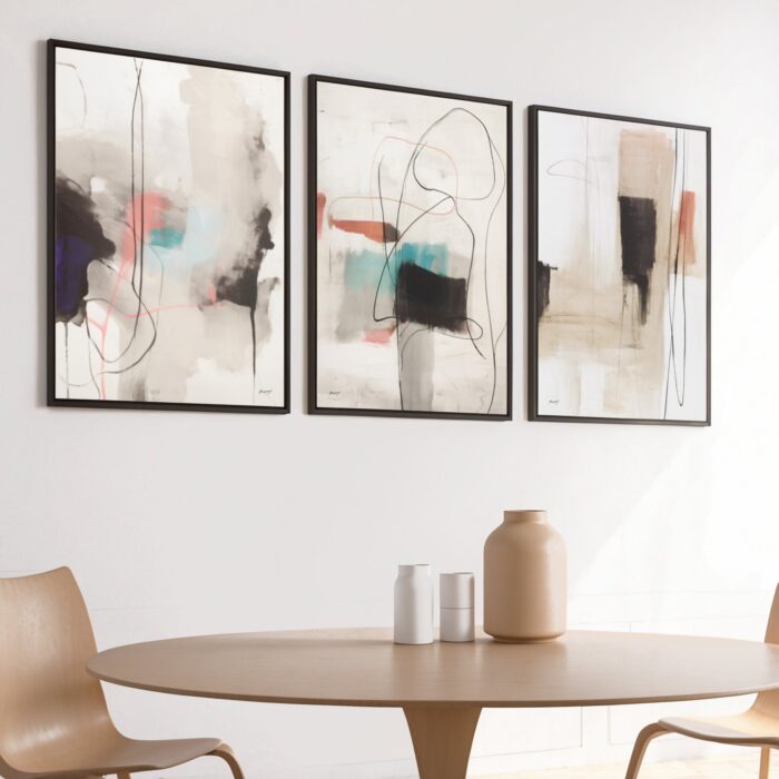 Abstract art triptych with black and beige brushstrokes above wooden dining table.