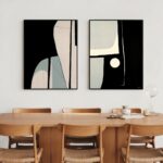 Abstract diptych artwork in black and beige tones above wooden mid-century dining table.