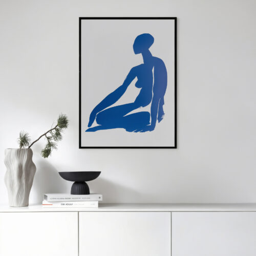 Blue figure silhouette artwork in black frame displayed above white cabinet with minimalist decor.