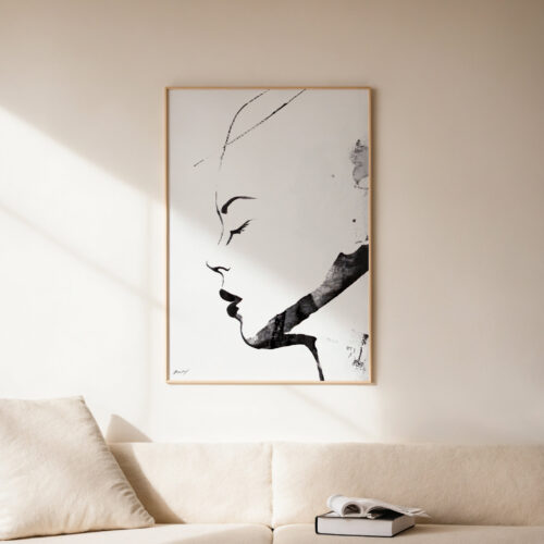 Minimalist black and white portrait on wall above neutral sofa in bright living room.
